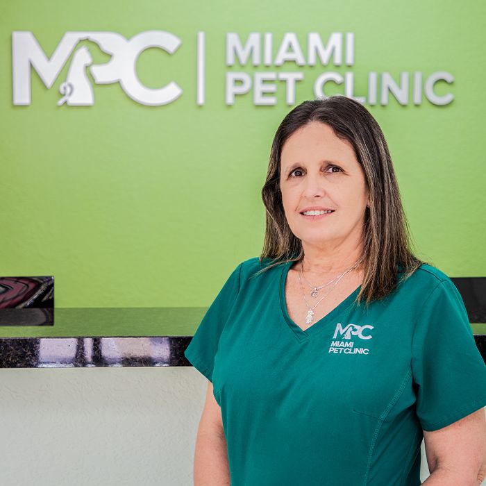 A woman in a green scrub top stands in front of a sign reading "Miami Pet Clinic."